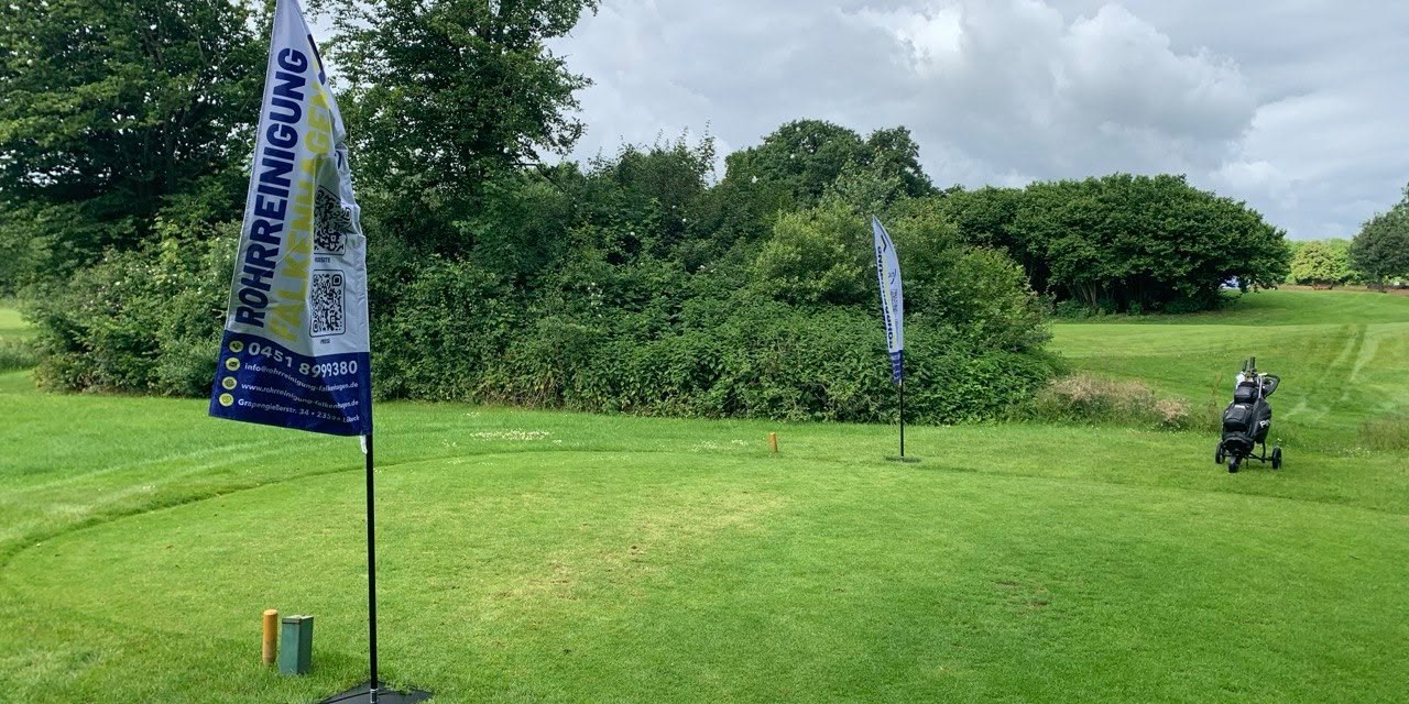 Zwei Werbefahnen der Rohrreinigung Falkenhagen stehen am Abschlag eines Golfplatzes