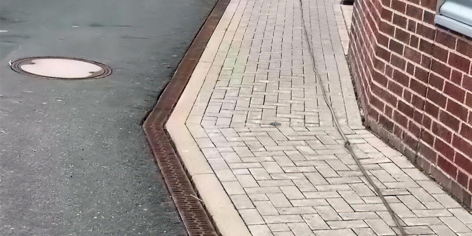 Über einen Industriehof verlegter Schlauch entlang einer Backsteinfassade, im Hintergrund Produktionsgebäude