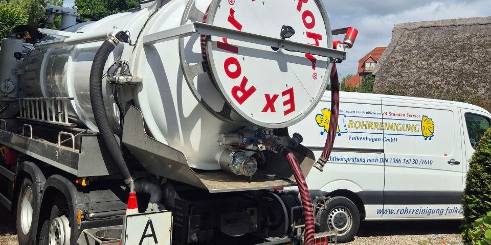 Saugwagen mit ausgelegtem Saugschlauch und daneben ein Servicefahrzeug der Rohrreinigung Falkenhagen auf einem Grundstück
